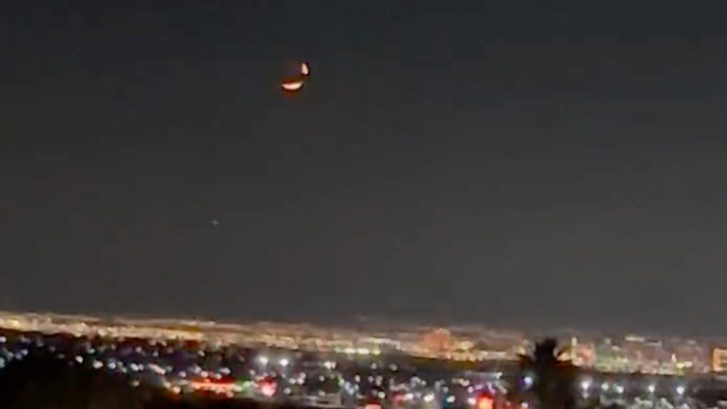 UFOs or the crescent moon above Las Vegas, orange cigar-shaped lights obscured by clouds in the sky